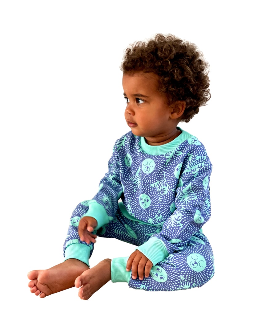 Little boy wearing vibrant green / purple African inspired lion face sweatshirt and joggers