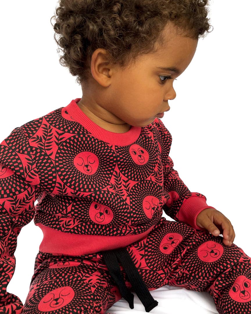 Little boy wearing red/black African inspired lion face sweatshirt and joggers
